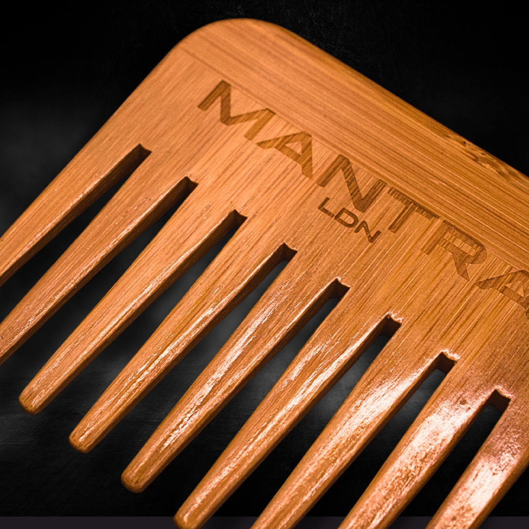 Wooden comb with 'MANTRA' branding on a dark background