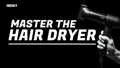 Hand holding a hair dryer with 'Heist' branding and text 'Master the Hair Dryer' on a black background.
